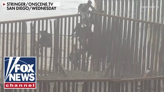 Shocking footage shows migrants breaching border wall