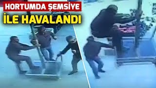 Şemsiye ile 'Uçan Adam' kamerada! Onu tutan arkadaşı ise çay bardağını bir an olsun bırakmadı