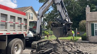 Bobcat E85 excavator ripping asphalt and loading trucks