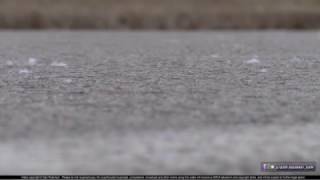 Snowflakes on pavement at the start of a dangerous icy road event