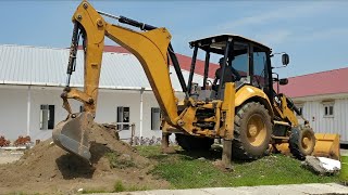 Action Operator Backhoe loader CAT 426F2 Digging the Ground into a Dump Truck