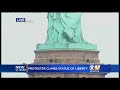 protester climbs on statue of liberty