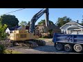 john deere excavator digging up road and loading dump truck