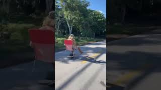 Guy Rides One Wheel With Red Lawn Chair On Road