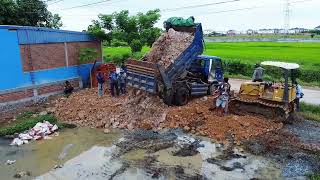 Bulldozer and 5ton Trucks Pouring soil into a flooded construction site