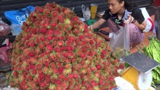 TROPICAL FRUIT IN THAILAND, LADIES SELLING PILES OF RAMBUTAN FRUIT IN THAILAND