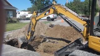 Caterpillar 304E CR Excavator Digging In A Street . Fixing water leak.