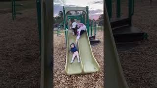 Mom falls down the slide because she's too scared to let go of her toddler!