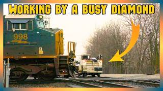 A crew stops close to a busy diamond for inspection as a train rolls through...