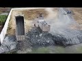 unbelievable big land slide into water and dump trucks try to loading so many stones into water