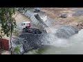 unbelievable big land slide into water and dump trucks try to loading so many stones into water