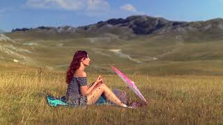 Meditation video - A woman enjoying a view of mountains and meadows.