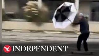 Skateboarder uses umbrella as sail in Hurricane Ian winds
