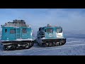 winter antarctic traverse tractor being escorted by two hagglunds