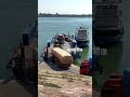 five large trucks lined up to board the ferry to cross the river. the ferryman content inspired