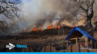 Wildfire engulfs hillside yards from village on major road