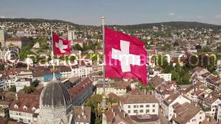 Aerial circling drone shot around Swiss flags on Grossmünster church in Zürich Switzerland closer