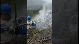 Hardworking worker drilling on cliff with simple tool