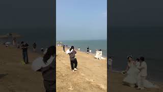 海边很多拍婚纱照的新人 Many new couples taking wedding photos on the beach