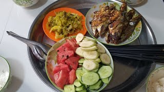 A simple yet delicious meal enjoyed with family: fried sea fish, watermelon, cucumber, and unripe...