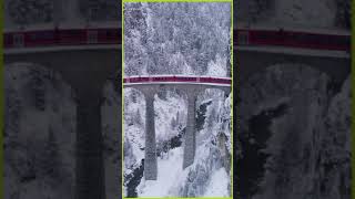 a train on the Landwasser Viaduct bridge in the snowy Swiss Alps