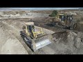 caterpillar d9t and komatsu d275 bulldozers pushing soil on huge mining area