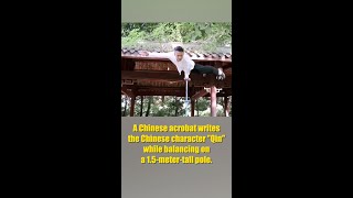 Chinese acrobat writes calligraphy while balancing on pole