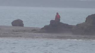 雨天の中地磯から竿を出すの釣人