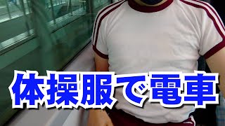 エンジのライン入り半袖体操服と短パンで電車に乗っている様子