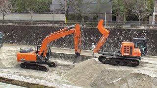 Japanese hydraulic shovels dig up river sediment.