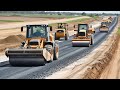 The process of road building with heavy machines working on a road. Gravel paving machine technology