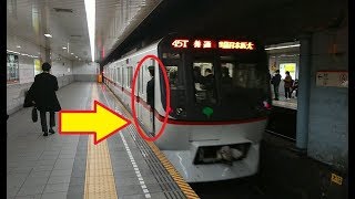 車掌が乗務員室のドアを開いて半身乗り出しによって夜の大門駅を出発する北総線に直通の都営浅草線下り5300形