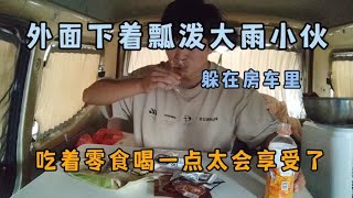 外面下着瓢泼大雨 小伙躲在房车里 吃着零食喝一点太会享受了