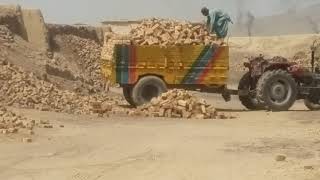 Hardworking people 2 laborers doing brick loading on a tractor