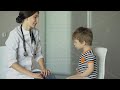 young woman doctor talking little boy and listening with stethoscope in medical office